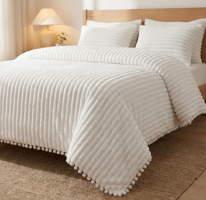 Cloudline comforter with pom-pom trim on a bed